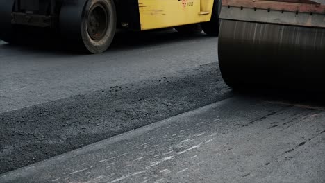 cleaning remaining asphalt on compressing, compacting, leveling and smoothing the asphalt road surface using tire roller and tandem roller