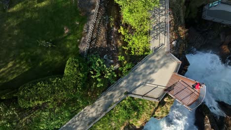 Man-flying-drone-over-waterfall-in-famous-Geiranger,-Norway