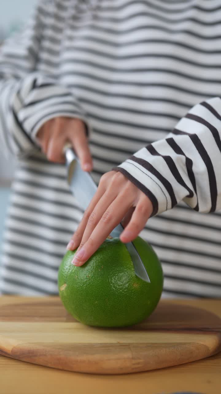 una mujer cortando un pomelo.