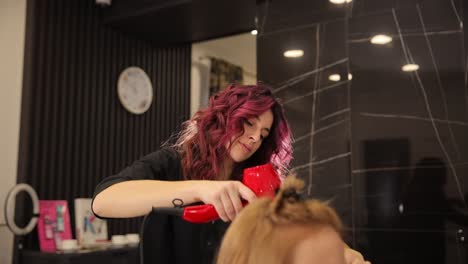 a talented stylist uses a bright red dryer to showcase unique techniques, creating beautiful, vibrant curls