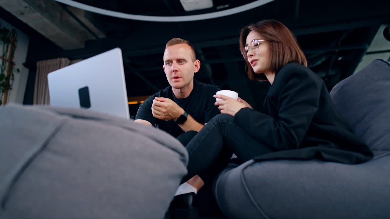 Mid-aged diverse colleague looking at laptop. Man and woman speak discussing work issues. Low angle view.