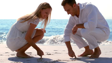 Happy-couple-drawing-heart-in-the-sand