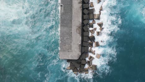 overhead shot of waves crashing on long pier with rocks, puerto de la cruz, spain