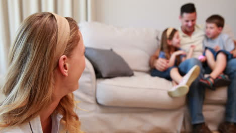 madre viendo a la familia en el sofá y sonriendo a la cámara