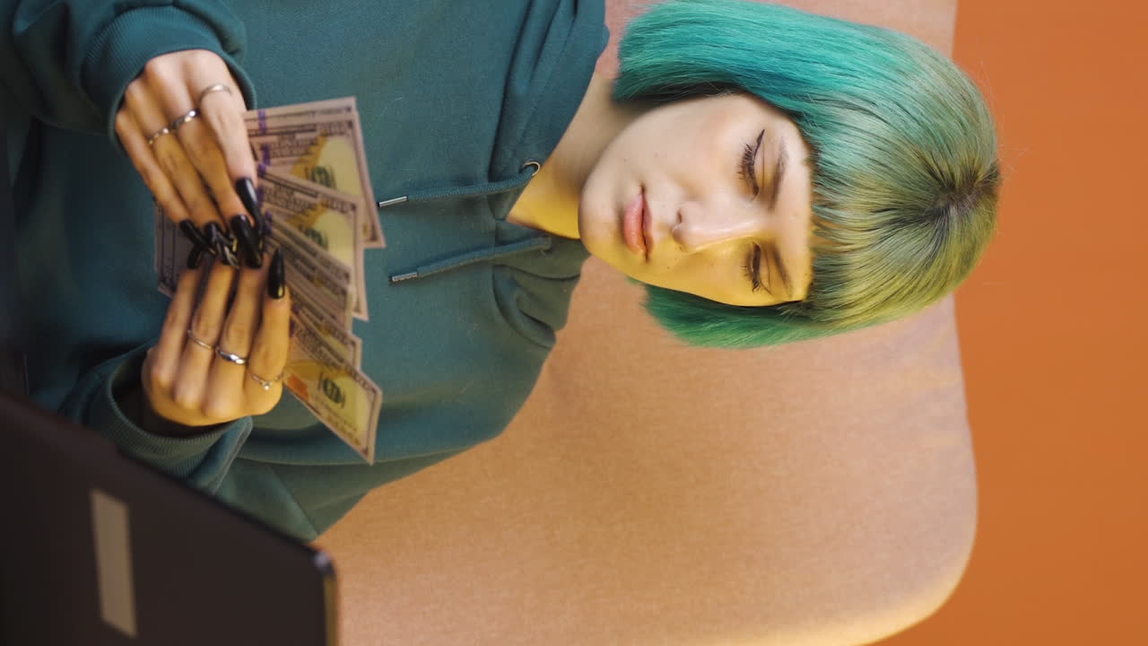 video vertical de una mujer joven mirando una computadora portátil contando dinero.