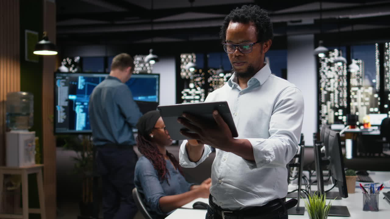 African American Man Working on Tablet in Modern Night Office