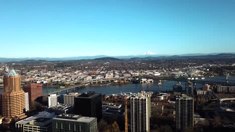 a panning aerial view of downtown portland with mount hood looming in the distance.
