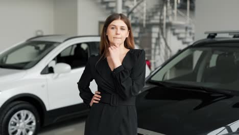 Hermosa-Chica-Con-Un-Vestido-Negro-Se-Encuentra-En-Un-Fondo-De-Autos-Reflexionando-Sobre-Comprar-Un-Auto