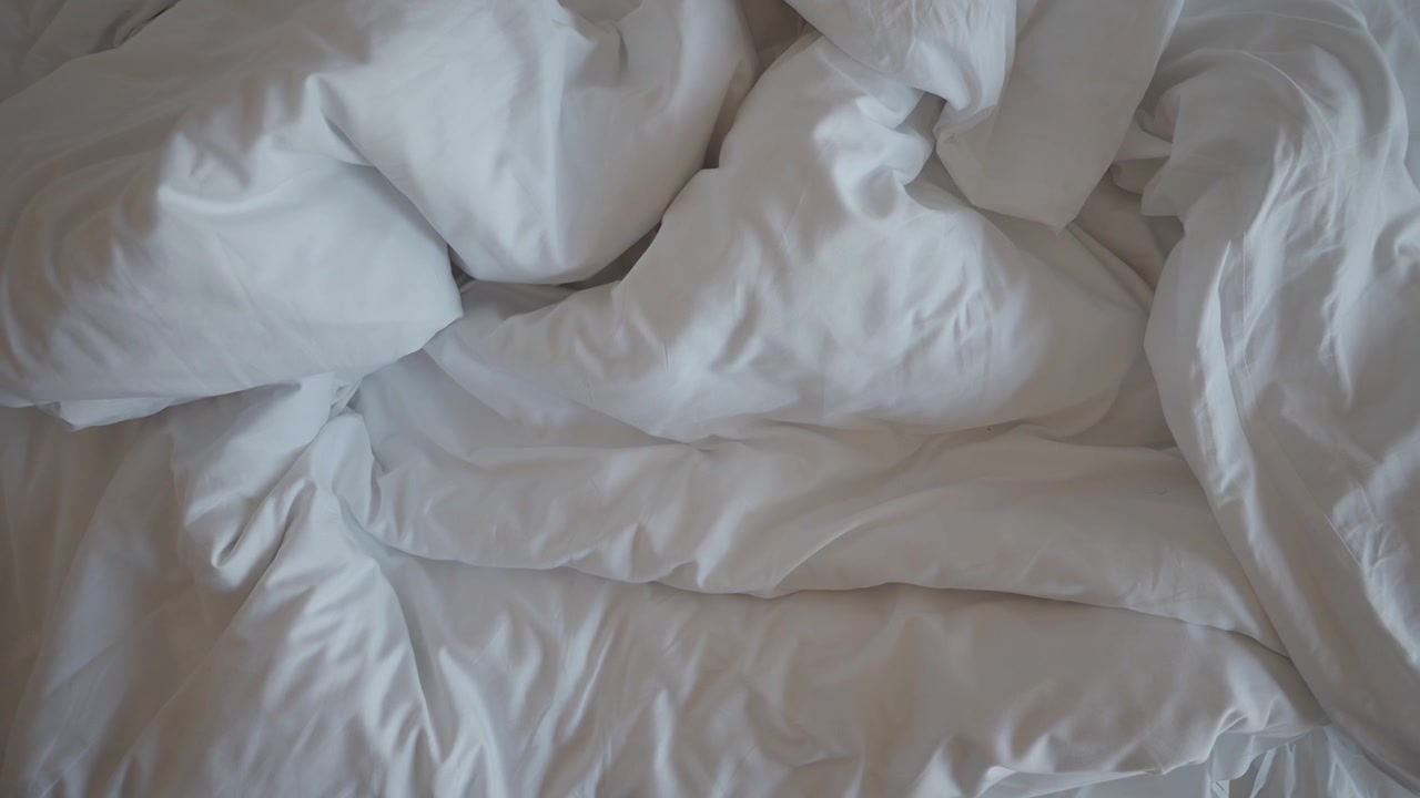 Tempat Tidur Putih yang Belum Dirapikan dengan Seprai dan Selimut Kusut