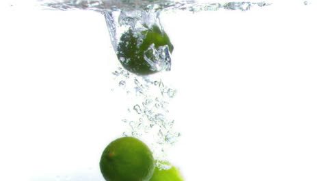 limes falling into water in super slow motion