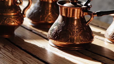 ornate copper coffee pots on wooden table