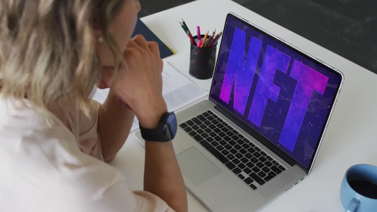 video de una mujer caucásica trabajando en una computadora portátil con nft en la pantalla