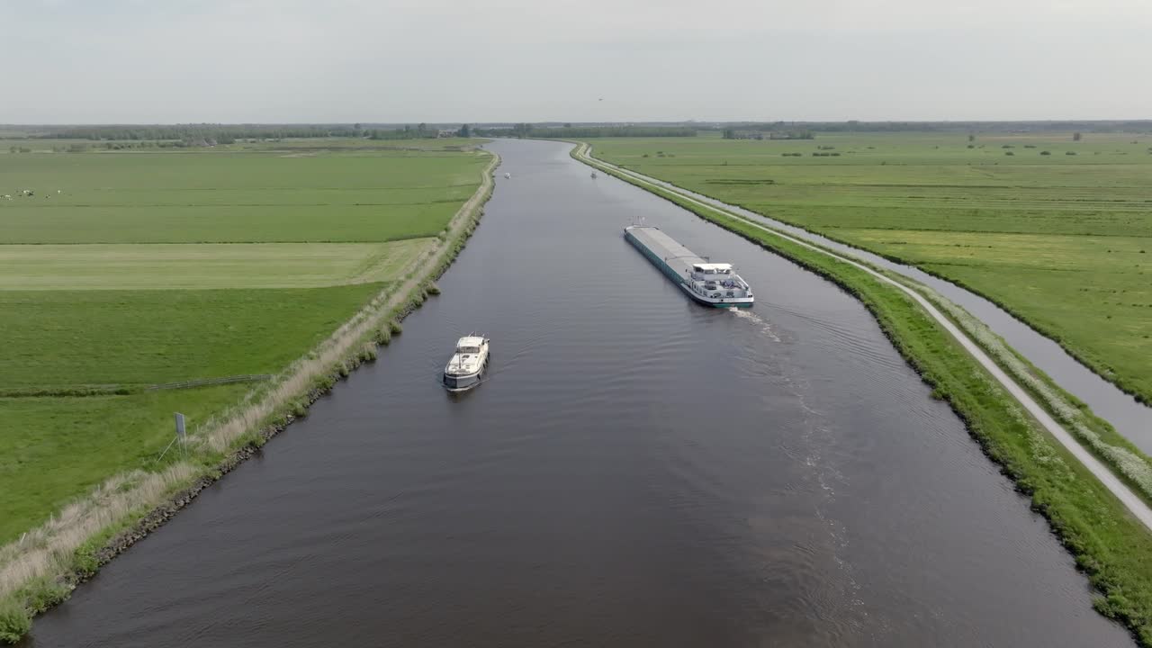 Boat And Barge Cruising In The Canal Along The Green Fields In Daytime In Netherlands. - aerial shot