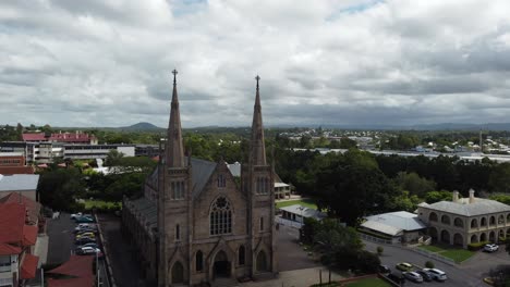 drone ascendiendo mostrando una gran iglesia católica y otros edificios en el fondo en australia