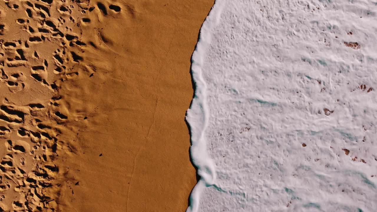 vista de pájaro de una ola fresca rompiendo en la mágica playa de arena, ericeira, portugal