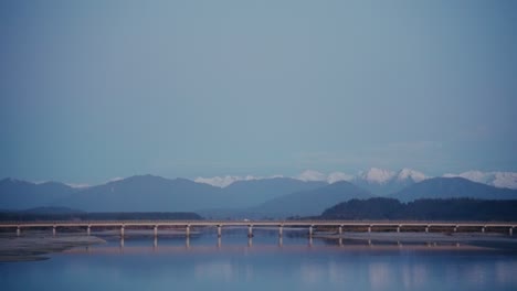 Car-Driving-Across-Bridge-in-Front-of-Mountains