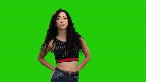 beautiful fit female holds hands in pockets and turns on green screen