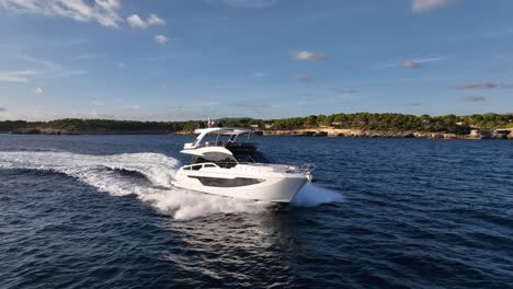 drone shot of luxury yacht driving next to coastline