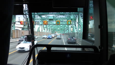 front view through windshield inside bus driving on bridge with cars traffic and lanes