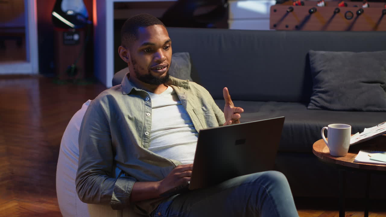 Vertical Video Young black person waving on remote video call on laptop sitting at home