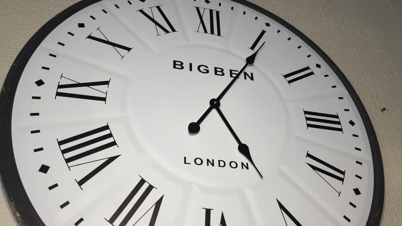 lapso de tiempo de un enorme reloj de pared de madera blanca con londres y big ben escrito en él, los minutos pasan rápidamente de las 5 de la tarde