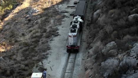 a man stands beside the tracks and watches a train as it goes by