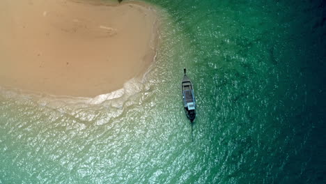 Longtail-boat-floating-at-island,-moving-clouds-shadow,-top-view