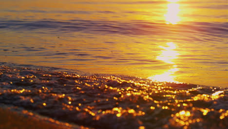 Primer-Plano-Olas-Del-Mar-Salpicando-Arena-De-La-Playa-Al-Amanecer-Dorado-De-La-Mañana.-Luz-De-Sol