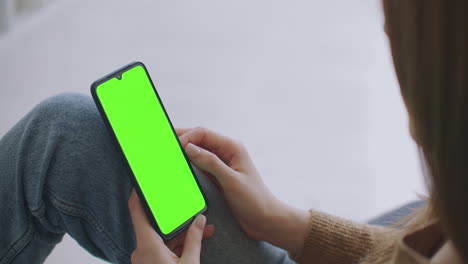 Phone-with-Green-Screen-and-Chroma-Key-Closeup.-Chromakey-Mockup-with-Tracking-Markers-and-Alpha-Matte.-POV-is-Vertical-Template-of-Device-in-Modern-House-Closeup.-Scroll-Up-Online-News-at-Cellphone