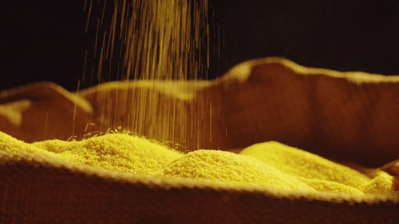 Yellow granules or cornmeal being poured into a sack