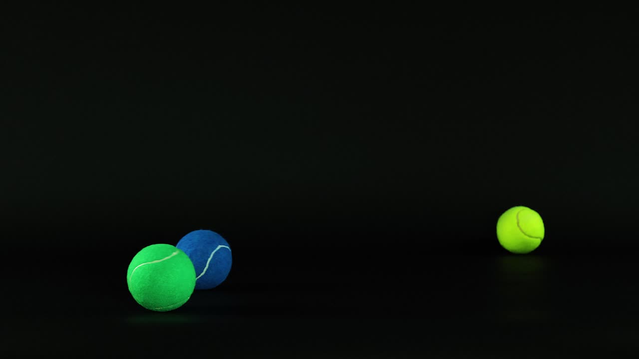 Various colored tennis balls moving in darkness