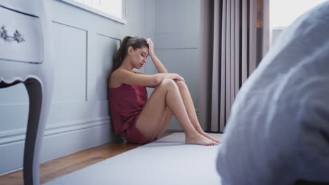 Mujer-Deprimida-En-Pijama-Sentada-En-El-Suelo-Del-Dormitorio