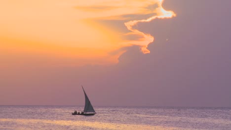 a beautiful dhow sailing boat glides along the coast of zanzibar at dusk