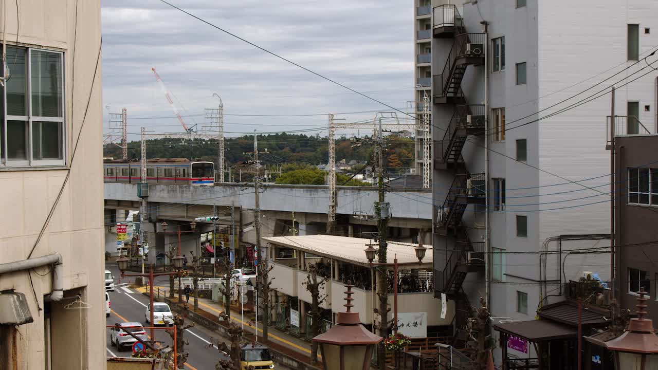 Commuter train passes over street on elevated track on grey morning