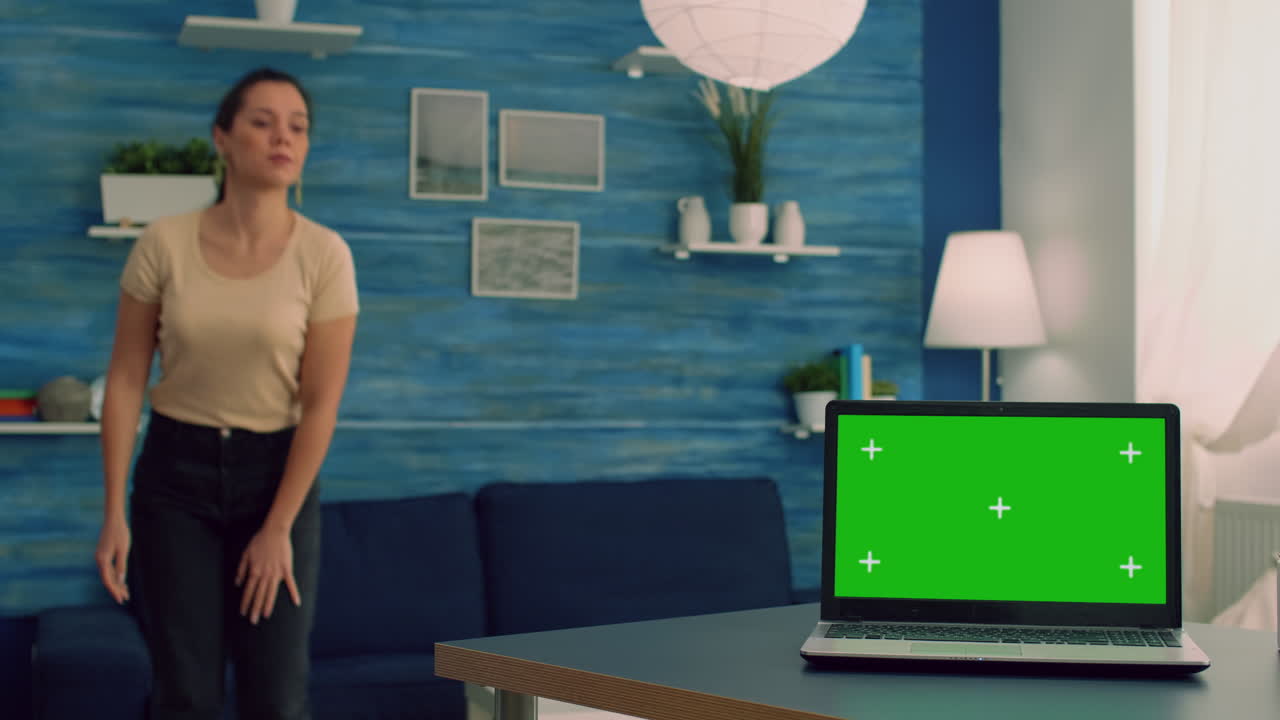 Caucasian female working on laptop computer with mock up green screen chroma key display
