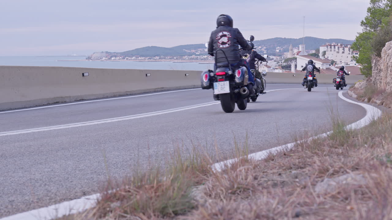 한 무리의 오토바이 운전자들이 구불구불한 도로를 타고 해안 도시로 향합니다.