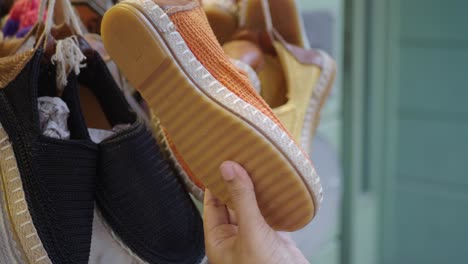 woman's hand holding orange espadrilles