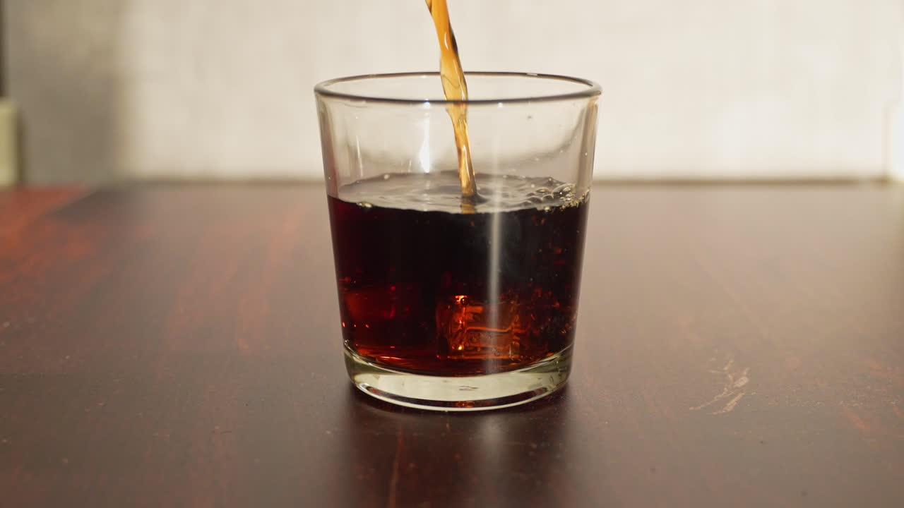 Il whisky si riversa in un bicchiere, formando increspature sulla superficie mentre il liquido dorato si posa sul tavolo