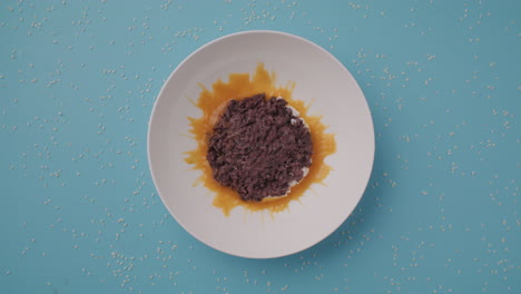 preparing a dish of dark purple rice with orange sauce and sesame seeds