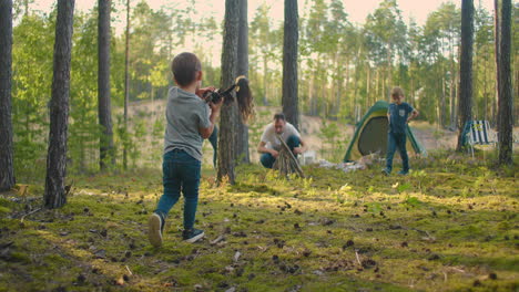 A-boy-collects-and-wears-sticks-for-a-campfire-during-a-hike.-Forest-caster-for-cooking-and-frying-marshmallows