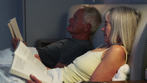 senior couple wearing pajamas lying in bed reading