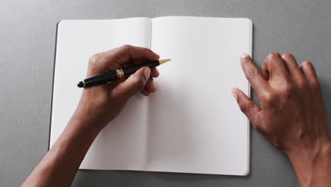 dichtbij van de hand schrijven met pen op boek met kopieerruimte op grijze achtergrond in slow motion