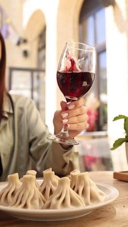 woman enjoying a glass of red wine and khinkali