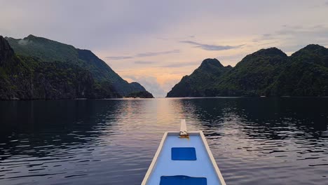 Boat-Sailing-Between-Small-Uninhabited-Tropical-Islands-at-Sunset,-Frontal-Point-of-View,-El-Nido,-Philippines