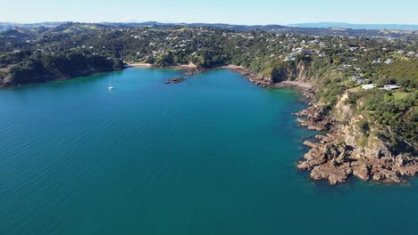 fishermans rock and turquoise ocean in oneroa, waiheke island, new zealand - aerial drone shot