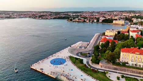 stunning aerial drone view of zadar’s old town at sunset, capturing the sea organ, greetings to the sun installation, deep blue adriatic, and golden-hour reflections.