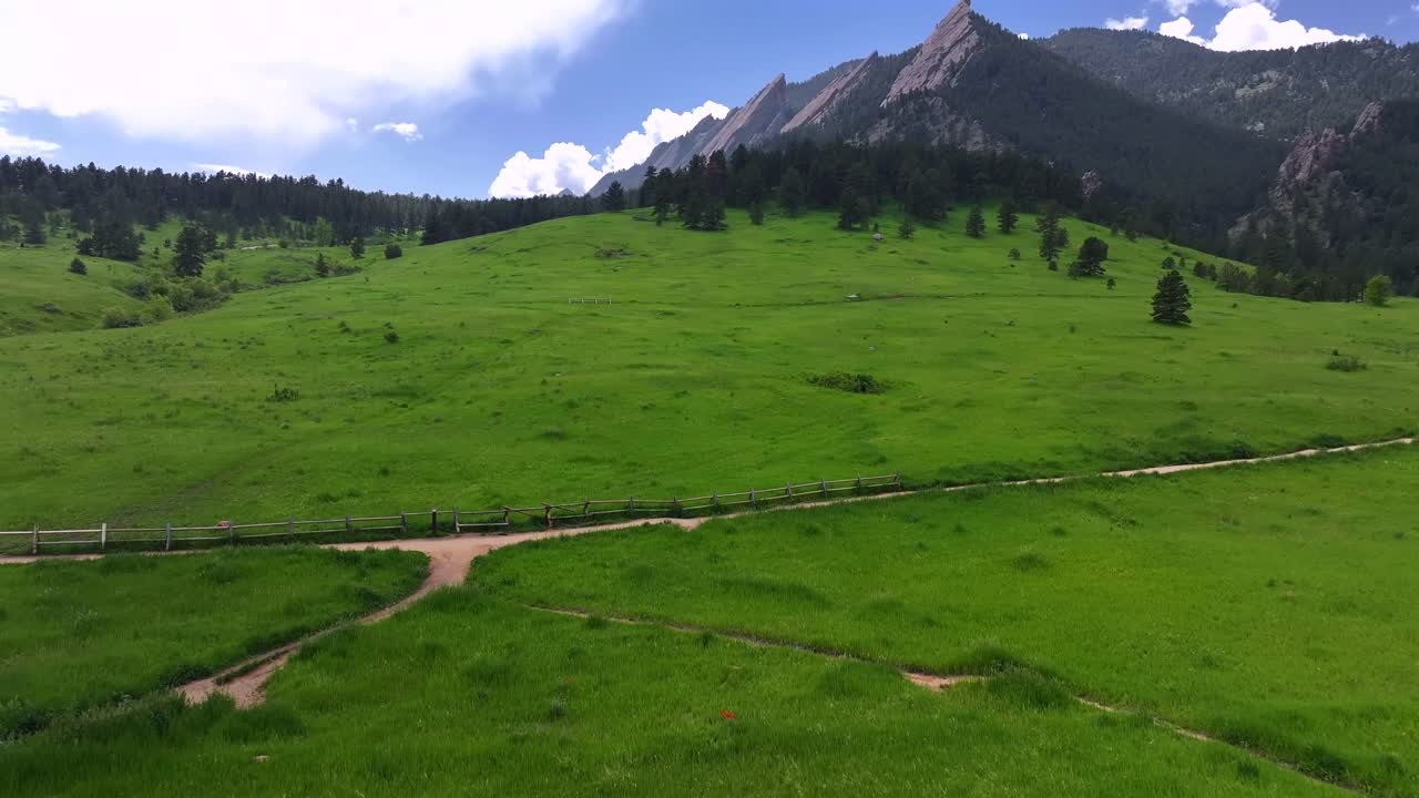 Spring summer morning blue sky Flatirons Chautauqua Park Boulder Colorado aerial drone Shanahan Ridge hiking trail Green Flatirons Mountain front range Rocky Mountains Royal Arch forward pan up motion