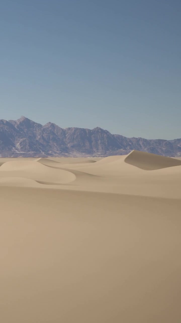 Dune di sabbia e montagne sotto un cielo azzurro nel deserto