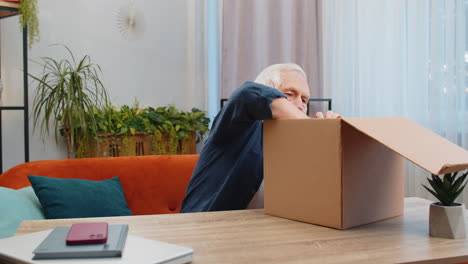 happy senior man shopper unpacking headphones cardboard box delivery parcel online shopping purchase