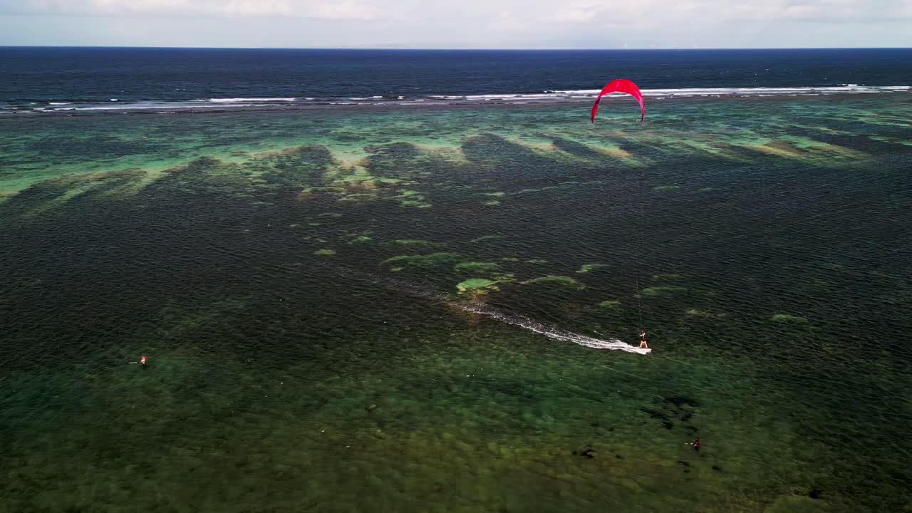 Aerial footage of Sanur Beach Bali shows a kite surfer harnessing the wind as turquoise waters and sandy coast create an unforgettable tropical seascape in drone video